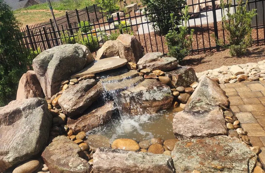 Cascading boulder falls built into an existing slope in a residential backyard. No site is too small for a custom water feature — we've built one in nearly every backyard of this Blaize Ridge community in Greer.