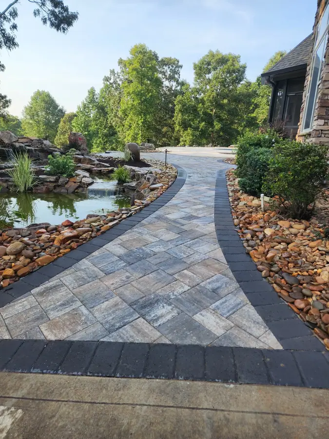 A curved paver walk laid in a herringbone field with a contrasting border, turning this side entrance into an inviting approach for guests at this Inman pool restoration.