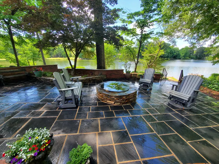 Flagstone patio with a stone fire pit set lakeside, laid to shed water away from the seating area. This Spartanburg gem sits right near the middle of town on the Eastside.