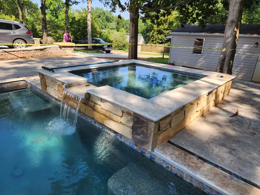 Pool, raised spa and a waterfall built entirely from stone — not a precast unit in sight. This downtown Greenville home now has a custom spa, pool, retaining walls and patio areas to match.